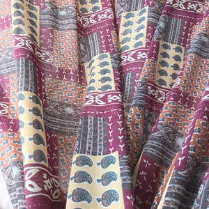 Puede incluir: Una tela con un diseño de patchwork que presenta varios patrones en tonos marrones, beige y morado. La tela tiene un patrón de paisley y un patrón geométrico.