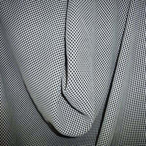 May include: Black and white gingham fabric with a textured weave. The fabric is folded and draped, showing the pattern and texture.