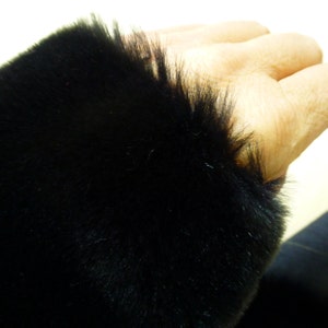 May include: Close-up of a black faux fur trim. The fur is soft and fluffy.