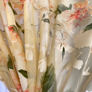 May include: A sheer curtain panel with a floral pattern in shades of pink, white, and green. The fabric is lightweight and translucent, creating a soft and airy feel.