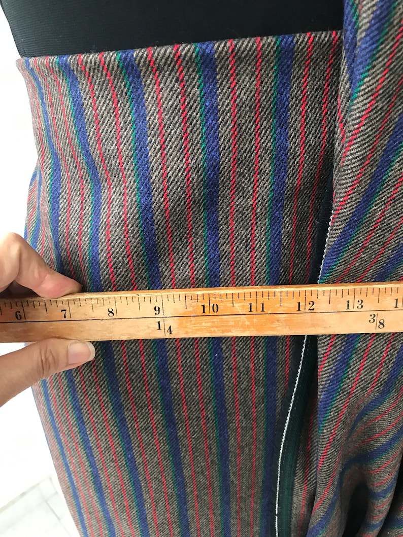 May include: Close-up of brown, blue, and red striped fabric with a ruler measuring 14 inches.