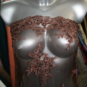May include: Brown beaded lace fabric with floral designs. The lace is sheer and delicate, with a subtle shimmer.
