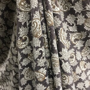 May include: Close-up of a brown fabric with a white and brown paisley pattern.