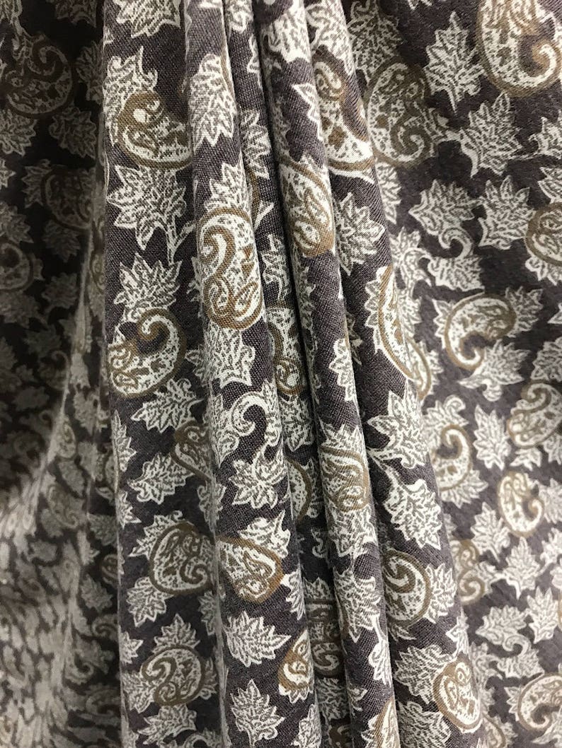 May include: Close-up of a brown fabric with a white and brown paisley pattern.