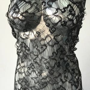 May include: Black lace fabric with a delicate floral pattern. The lace has a shimmery finish.
