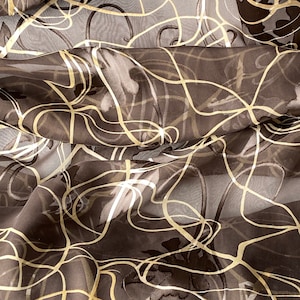 May include: A sheer fabric with a brown and gold floral pattern. The fabric is translucent and has a delicate, flowing texture.