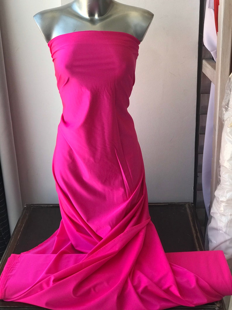 May include: A bright pink fabric swatch draped over a mannequin. The fabric is smooth and has a slight sheen.