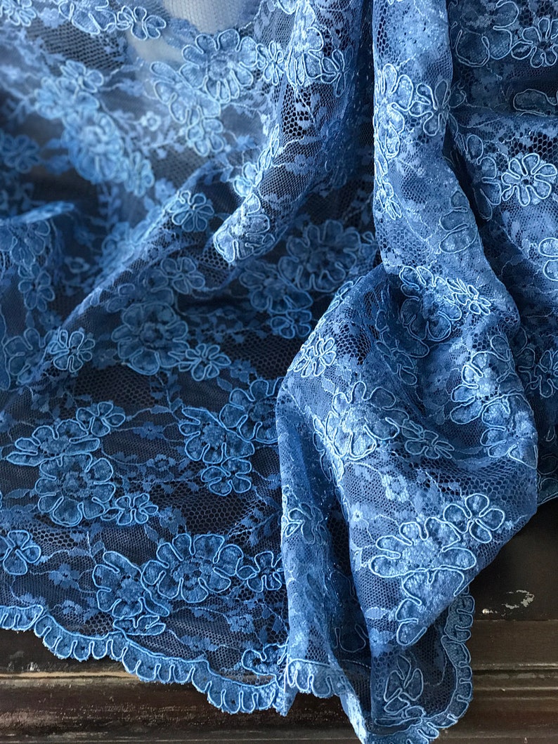 Op de afbeelding: Blauwe kant met een bloemenpatroon. De kant heeft een gegolfde rand.