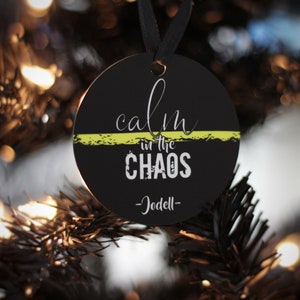 May include: Black round Christmas ornament with a yellow stripe and the text "calm in the CHAOS -Jodell-"