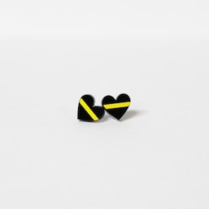 May include: A pair of black heart-shaped earrings with a thin yellow stripe across the center of each heart.
