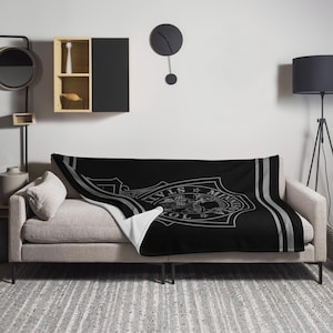 May include: Black and white throw blanket with a gray and white design featuring the text "ALVIS MINNEAPOLIS POLICE". The blanket is on a gray couch with a white pillow.