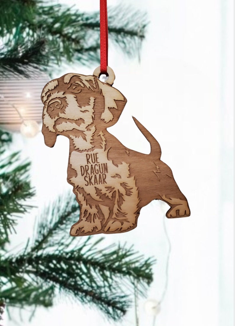 May include: A wooden Christmas ornament shaped like a dog with the text "RUE DRAGUN SKAAR" engraved on the front.