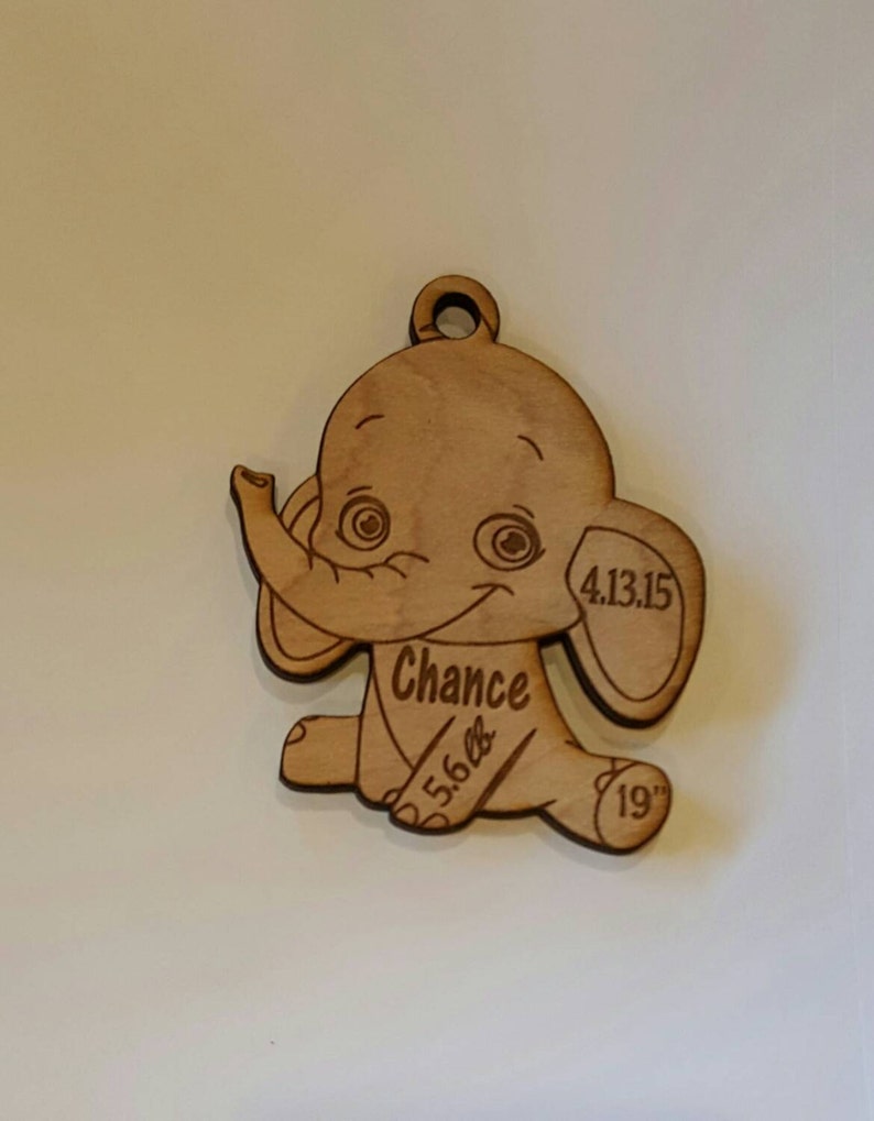 May include: Wooden elephant ornament with the name "Chance" and the date "4.13.15" engraved on it. The ornament also includes the measurements "5.6 lbs" and "19" inches.