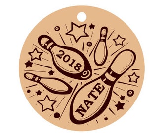 May include: A round, tan-colored tag with a hole at the top, featuring a bowling theme. The design includes several bowling pins, stars, and the name "NATE" and the year "2018" in a dark brown color. The style is reminiscent of a vintage illustration.