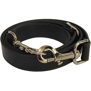 May include: A black leather strap with a silver metal hook and loop closure. The strap is folded in half and the hook is attached to the loop.