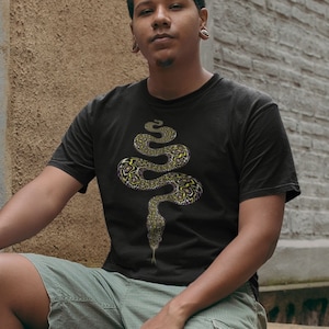Op de afbeelding: Een zwart T-shirt met een afbeelding van een gele en zwarte slang. De slang is verticaal opgerold.