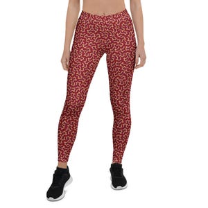 May include: Red leggings with a yellow abstract pattern. The leggings are fitted and have a high waist.