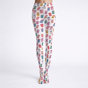 Op de afbeelding: Witte legging met een herhaald patroon van kleine, rechthoekige illustraties in roze, blauw, geel en groen. De illustraties hebben verschillende ontwerpen en details. De legging is nauwsluitend.