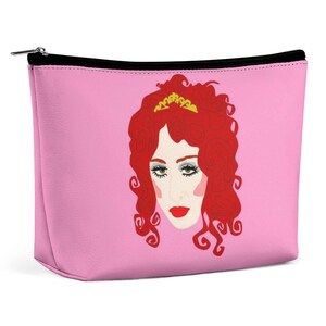 Könnte beinhalten: Rosa Kosmetiktasche mit Reißverschluss und einer Cartoon-Illustration einer Frau mit roten Haaren und einer goldenen Krone.