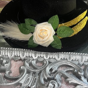 May include: A white ceramic mug with a black handle and the text "But First, Coffee" in a bold, black font. The mug is set against a blurred background, suggesting a cozy setting.