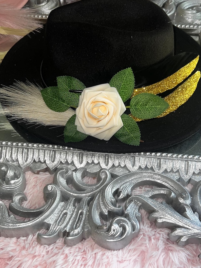 May include: A white ceramic mug with a black handle and the text "But First, Coffee" in a bold, black font. The mug is set against a blurred background, suggesting a cozy setting.