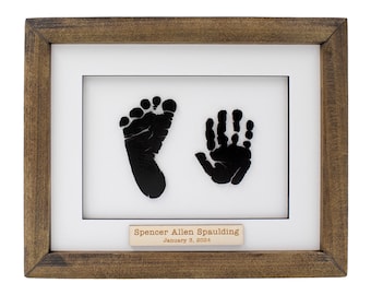 May include: A framed black and white baby footprint and handprint with a personalized nameplate that reads "Spencer Allen Spaulding January 3, 2024".