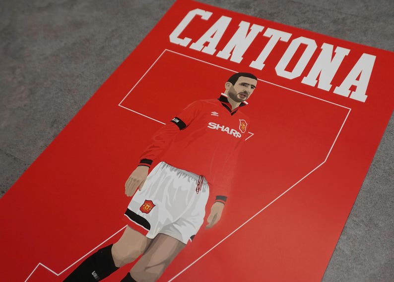 May include: Red poster featuring a stylized illustration of a soccer player in a red jersey with the name "CANTONA" in white block letters. The player is wearing white shorts and black socks. The jersey has the "SHARP" logo.