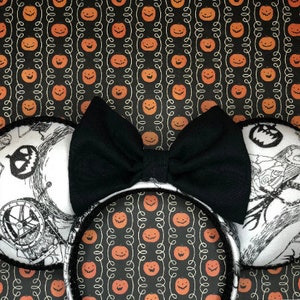 May include: Black and white mouse ears with a black bow. The ears feature a black and white illustration of Jack Skellington from the Nightmare Before Christmas.