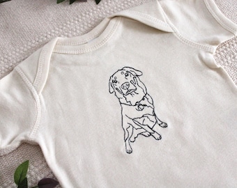 May include: A white baby onesie with a black embroidered image of a dog.