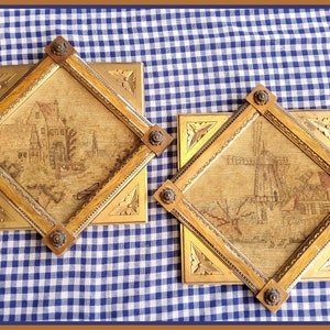 May include: Two framed needlepoint pictures with gold frames and ornate corners. The pictures depict a building and a windmill.