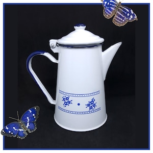 Può includere: Caffettiera in smalto bianco con un motivo floreale blu e un manico blu. La caffettiera ha un coperchio e un beccuccio.