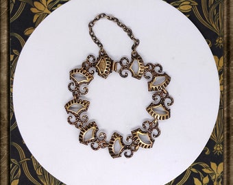 May include: A gold-toned bracelet with a delicate, intricate design. The bracelet is made up of a series of small, fan-shaped links that are connected by a chain.