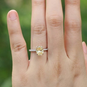 May include: A silver ring with a large oval-shaped yellow gemstone surrounded by smaller clear gemstones.