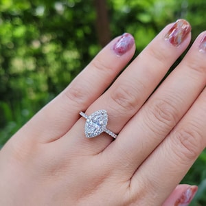 May include: A silver ring with a marquise-shaped diamond set in a halo of smaller diamonds.