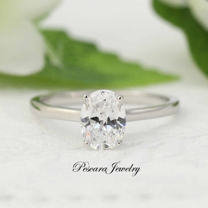 May include: A silver solitaire engagement ring with an oval-shaped diamond.