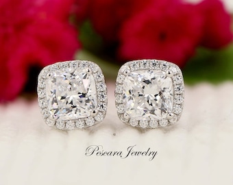 May include: A pair of silver earrings featuring a square-shaped cubic zirconia stone with a halo of smaller cubic zirconia stones.