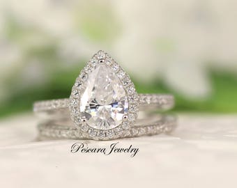 Op de afbeelding: Een peervormige verlovingsring met een halo-setting en een bijpassende trouwring. De ring is bezet met heldere zirkonia-stenen.
