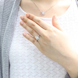 May include: A pear-shaped diamond engagement ring with a halo of smaller diamonds set in a white gold band.