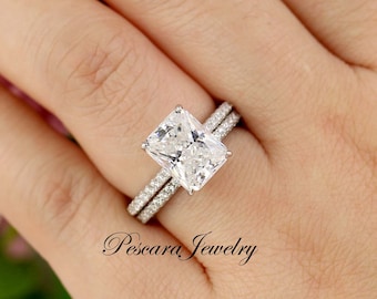 May include: A silver engagement ring set with a large, rectangular, clear, cubic zirconia stone. The ring is set with smaller cubic zirconia stones on the band.