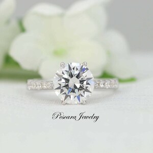 May include: A silver engagement ring with a large, round, clear diamond center stone and a band of smaller diamonds.