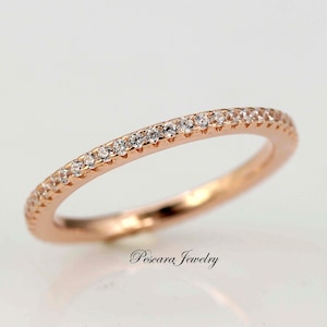May include: A rose gold band ring with a row of small clear diamonds set around the edge.