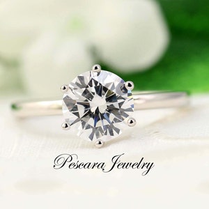 May include: A silver ring with a large, clear, round-cut diamond.