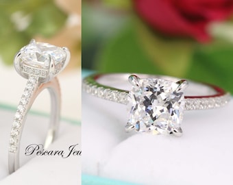 May include: A silver engagement ring with a large, square-shaped, clear gemstone. The ring has a band of small, clear gemstones.