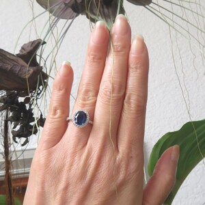 May include: A silver ring with a large oval blue sapphire surrounded by a halo of smaller diamonds.