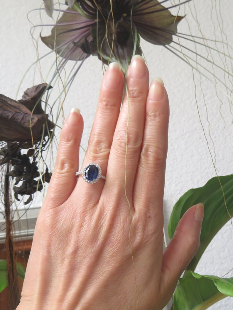 May include: A silver ring with a large oval blue sapphire surrounded by a halo of smaller diamonds.