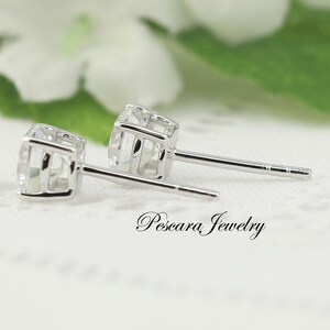 May include: A pair of silver stud earrings featuring clear cubic zirconia stones. The earrings have a simple, elegant design and are ideal for everyday wear.