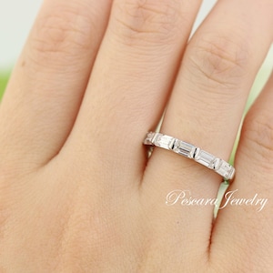 May include: A silver band with a row of rectangular-shaped diamonds set in a channel setting.