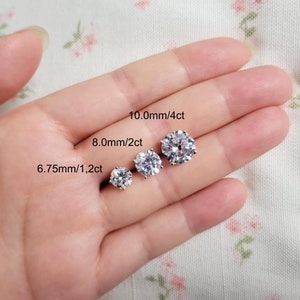 Op de afbeelding: Drie ronde, heldere zirkonia oorbellen in verschillende maten. De oorbellen zijn 6,75 mm/1,2 ct, 8,0 mm/2 ct en 10,0 mm/4 ct.