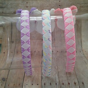 Puede incluir: Cuatro diademas coloridas con diferentes dise&ntilde;os de patrones. Las diademas est&aacute;n hechas de una cinta blanca y rosa con una base blanca y un patr&oacute;n rosa, morado o azul claro.
