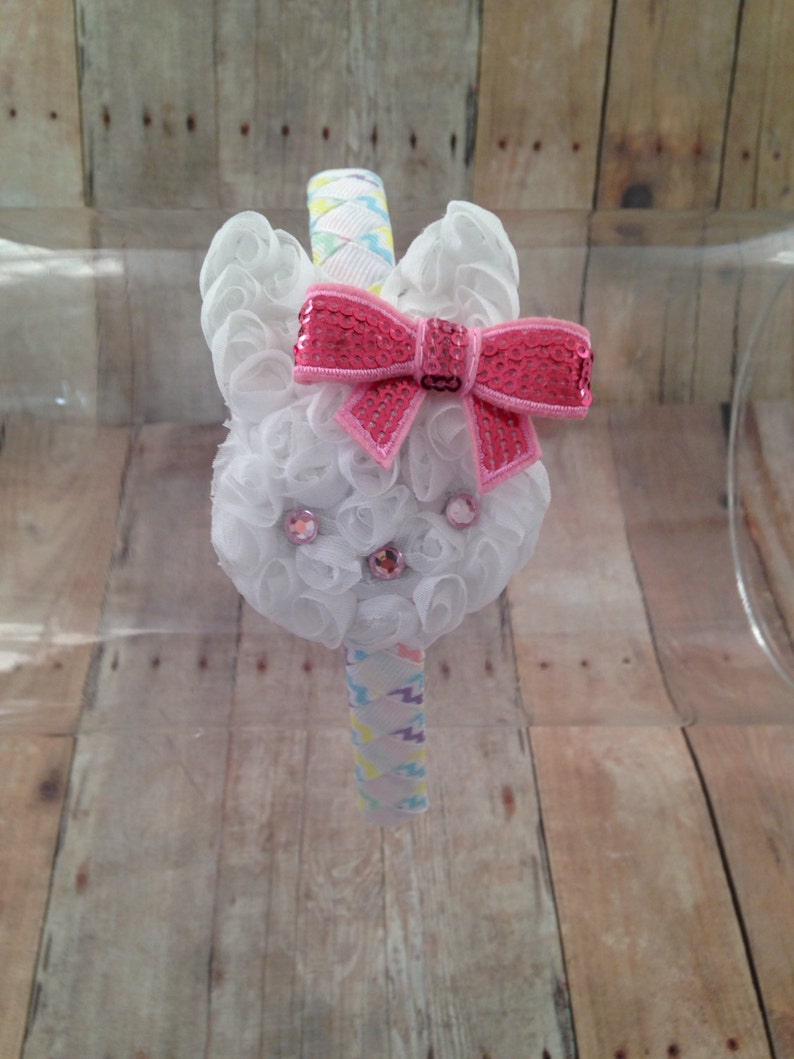 Puede incluir: Diadema de conejito blanco con un lazo rosa de lentejuelas y pedrer&iacute;a. La diadema est&aacute; decorada con una cinta de colores.